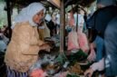 Seorang wanita modern menikmati segelas jamu kunyit asam segar di sebuah kafe jamu kekinian, menunjukkan bagaimana minuman tradisional ini telah beradaptasi dengan gaya hidup urban. Berbagai rempah seperti jahe, kunyit, dan kencur yang menjadi bahan dasar jamu tampak tertata rapi di latar belakang, mengisyaratkan kekayaan alam Indonesia.