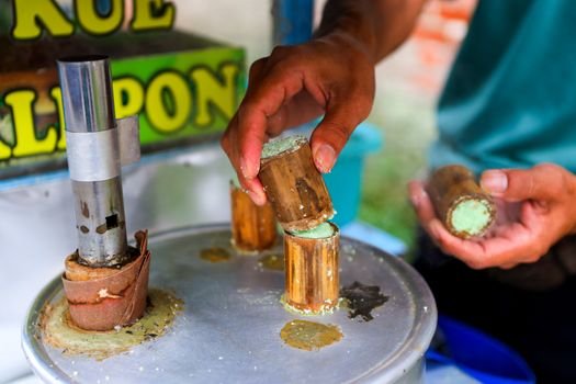 Penjual surabi tradisional sedang memanggang adonan di atas tungku arang, menciptakan aroma khas yang menggoda selera di sebuah sudut kota Bandung. Hidangan sederhana ini seringkali disajikan hangat dengan aneka topping, mulai dari yang klasik hingga modern.