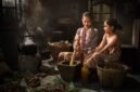 Seorang penjual jamu gendong tengah menyajikan ramuan kunyit asam yang segar, menampilkan kekayaan tradisi kuliner dan kesehatan Indonesia yang sudah ada sejak ratusan tahun silam.