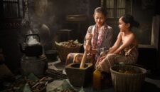 Seorang penjual jamu gendong tengah menyajikan ramuan kunyit asam yang segar, menampilkan kekayaan tradisi kuliner dan kesehatan Indonesia yang sudah ada sejak ratusan tahun silam.