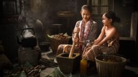 Seorang penjual jamu gendong tengah menyajikan ramuan kunyit asam yang segar, menampilkan kekayaan tradisi kuliner dan kesehatan Indonesia yang sudah ada sejak ratusan tahun silam.