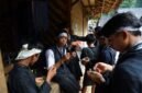 Seorang nenek di pedesaan Sunda sedang meracik ramuan herbal menggunakan tumbuk tradisional, menunjukkan kearifan turun-temurun dalam mengolah tanaman obat alami. Berbagai jenis dedaunan dan akar terlihat di sekelilingnya, siap diolah menjadi obat untuk menjaga kesehatan.