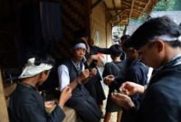 Seorang nenek di pedesaan Sunda sedang meracik ramuan herbal menggunakan tumbuk tradisional, menunjukkan kearifan turun-temurun dalam mengolah tanaman obat alami. Berbagai jenis dedaunan dan akar terlihat di sekelilingnya, siap diolah menjadi obat untuk menjaga kesehatan.