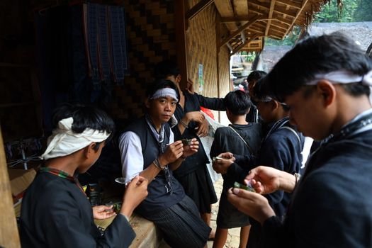 Seorang nenek di pedesaan Sunda sedang meracik ramuan herbal menggunakan tumbuk tradisional, menunjukkan kearifan turun-temurun dalam mengolah tanaman obat alami. Berbagai jenis dedaunan dan akar terlihat di sekelilingnya, siap diolah menjadi obat untuk menjaga kesehatan.