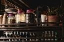 Suasana nyaman sebuah kafe jamu modern yang menyajikan ramuan herbal tradisional Indonesia dengan sentuhan kekinian, menarik minat generasi muda untuk menikmati manfaat kesehatan alami. Berbagai botol jamu dengan kemasan menarik tertata rapi, menunjukkan evolusi minuman warisan budaya ini agar tetap relevan dengan gaya hidup urban.