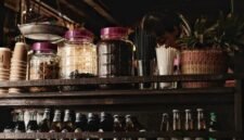 Suasana nyaman sebuah kafe jamu modern yang menyajikan ramuan herbal tradisional Indonesia dengan sentuhan kekinian, menarik minat generasi muda untuk menikmati manfaat kesehatan alami. Berbagai botol jamu dengan kemasan menarik tertata rapi, menunjukkan evolusi minuman warisan budaya ini agar tetap relevan dengan gaya hidup urban.