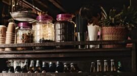 Suasana nyaman sebuah kafe jamu modern yang menyajikan ramuan herbal tradisional Indonesia dengan sentuhan kekinian, menarik minat generasi muda untuk menikmati manfaat kesehatan alami. Berbagai botol jamu dengan kemasan menarik tertata rapi, menunjukkan evolusi minuman warisan budaya ini agar tetap relevan dengan gaya hidup urban.