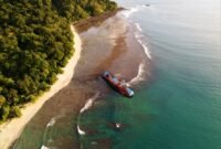 Pemandangan matahari terbenam yang memukau di Pantai Pangandaran, dengan siluet perahu nelayan tradisional yang menambah keindahan suasana senja. Pengunjung juga dapat menikmati keseruan *body rafting* di Green Canyon atau menyelami keindahan bawah laut di Pasir Putih Pangandaran.
