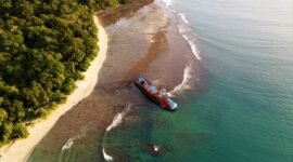 Pemandangan matahari terbenam yang memukau di Pantai Pangandaran, dengan siluet perahu nelayan tradisional yang menambah keindahan suasana senja. Pengunjung juga dapat menikmati keseruan *body rafting* di Green Canyon atau menyelami keindahan bawah laut di Pasir Putih Pangandaran.
