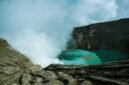 Pemandangan udara Kawah Putih Ciwidey yang menakjubkan, menunjukkan danau kawah berwarna putih kehijauan dikelilingi lanskap pegunungan yang asri. Visual ini memperlihatkan keunikan geologis dan keindahan alam yang menjadi daya tarik utama destinasi wisata populer tersebut.
