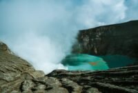 Pemandangan udara Kawah Putih Ciwidey yang menakjubkan, menunjukkan danau kawah berwarna putih kehijauan dikelilingi lanskap pegunungan yang asri. Visual ini memperlihatkan keunikan geologis dan keindahan alam yang menjadi daya tarik utama destinasi wisata populer tersebut.