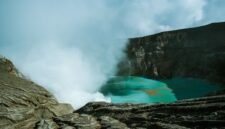 Pemandangan udara Kawah Putih Ciwidey yang menakjubkan, menunjukkan danau kawah berwarna putih kehijauan dikelilingi lanskap pegunungan yang asri. Visual ini memperlihatkan keunikan geologis dan keindahan alam yang menjadi daya tarik utama destinasi wisata populer tersebut.