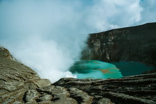 Pemandangan udara Kawah Putih Ciwidey yang menakjubkan, menunjukkan danau kawah berwarna putih kehijauan dikelilingi lanskap pegunungan yang asri. Visual ini memperlihatkan keunikan geologis dan keindahan alam yang menjadi daya tarik utama destinasi wisata populer tersebut.
