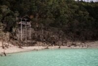 Pemandangan Kawah Putih Ciwidey dengan danau berwarna pirus kehijauan yang kontras dengan tebing kapur putih, menciptakan lanskap surealistik memukau. Udara sejuk pegunungan dan aroma belerang khas menambah pengalaman unik saat menjelajahi keindahan alam ini.
