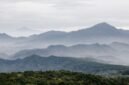 Ilustrasi artistik yang menggambarkan adegan Sangkuriang menendang perahu hingga terbalik, membentuk Gunung Tangkuban Parahu, dengan Dayang Sumbi dan suasana pedesaan di latar belakang. Gambar ini menunjukkan puncak drama dalam legenda populer tersebut.