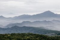 Ilustrasi artistik yang menggambarkan adegan Sangkuriang menendang perahu hingga terbalik, membentuk Gunung Tangkuban Parahu, dengan Dayang Sumbi dan suasana pedesaan di latar belakang. Gambar ini menunjukkan puncak drama dalam legenda populer tersebut.