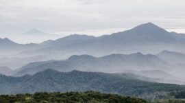 Ilustrasi artistik yang menggambarkan adegan Sangkuriang menendang perahu hingga terbalik, membentuk Gunung Tangkuban Parahu, dengan Dayang Sumbi dan suasana pedesaan di latar belakang. Gambar ini menunjukkan puncak drama dalam legenda populer tersebut.