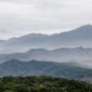 Ilustrasi artistik yang menggambarkan adegan Sangkuriang menendang perahu hingga terbalik, membentuk Gunung Tangkuban Parahu, dengan Dayang Sumbi dan suasana pedesaan di latar belakang. Gambar ini menunjukkan puncak drama dalam legenda populer tersebut.