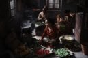 Seorang penjual sedang membuat surabi di atas tungku arang tradisional, menunjukkan proses otentik yang menjaga cita rasa khas jajanan legendaris ini. Asap tipis mengepul dari cetakan, menambah daya tarik visual dari kuliner khas Bandung yang selalu dicari ini.