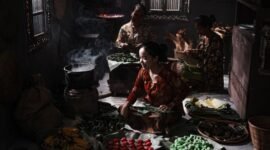 Seorang penjual sedang membuat surabi di atas tungku arang tradisional, menunjukkan proses otentik yang menjaga cita rasa khas jajanan legendaris ini. Asap tipis mengepul dari cetakan, menambah daya tarik visual dari kuliner khas Bandung yang selalu dicari ini.