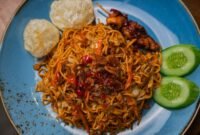 Sebuah mangkuk seblak Bandung disajikan hangat dengan beragam topping seperti ceker, bakso, dan kerupuk, memancarkan aroma pedas kencur yang menggugah selera. Hidangan ini menunjukkan perpaduan sempurna antara tekstur kenyal dan kuah pedas gurih yang menjadi daya tarik utama kuliner ikonik kota kembang.