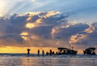 Indahnya siluet perahu nelayan tradisional saat matahari terbenam di Pantai Barat Pangandaran, menciptakan pemandangan ikonik yang menenangkan jiwa para pengunjung.
