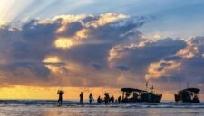 Indahnya siluet perahu nelayan tradisional saat matahari terbenam di Pantai Barat Pangandaran, menciptakan pemandangan ikonik yang menenangkan jiwa para pengunjung.