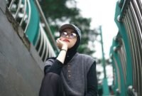 Seorang pemuda bergaya kasual dengan jaket denim dan kaus grafis dari distro lokal, menunjukkan semangat berbusana yang unik dan otentik di tengah keramaian kota. Pilihan gaya ini merefleksikan identitas diri serta dukungan terhadap karya desainer muda Indonesia.