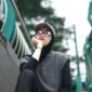 Seorang pemuda bergaya kasual dengan jaket denim dan kaus grafis dari distro lokal, menunjukkan semangat berbusana yang unik dan otentik di tengah keramaian kota. Pilihan gaya ini merefleksikan identitas diri serta dukungan terhadap karya desainer muda Indonesia.