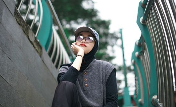 Seorang pemuda bergaya kasual dengan jaket denim dan kaus grafis dari distro lokal, menunjukkan semangat berbusana yang unik dan otentik di tengah keramaian kota. Pilihan gaya ini merefleksikan identitas diri serta dukungan terhadap karya desainer muda Indonesia.