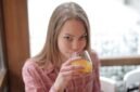 Seorang perempuan muda menikmati segelas jamu kunyit asam di sebuah kafe modern, menunjukkan bagaimana ramuan tradisional ini kini menjadi bagian gaya hidup sehat urban. Racikan herbal ini menawarkan kesegaran dan khasiat alami yang telah diwariskan turun-temurun.