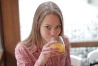 Seorang perempuan muda menikmati segelas jamu kunyit asam di sebuah kafe modern, menunjukkan bagaimana ramuan tradisional ini kini menjadi bagian gaya hidup sehat urban. Racikan herbal ini menawarkan kesegaran dan khasiat alami yang telah diwariskan turun-temurun.