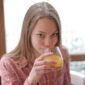 Seorang perempuan muda menikmati segelas jamu kunyit asam di sebuah kafe modern, menunjukkan bagaimana ramuan tradisional ini kini menjadi bagian gaya hidup sehat urban. Racikan herbal ini menawarkan kesegaran dan khasiat alami yang telah diwariskan turun-temurun.