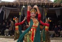 Seorang penari Jaipong dengan kostum warna-warni dan selendang yang melambai anggun, tengah menampilkan gerakan lincah penuh ekspresi, mencerminkan semangat khas tarian tradisional Sunda. Tarian ini memadukan kekuatan dan keanggunan, menjadi identitas budaya yang terus dijaga kelestariannya.