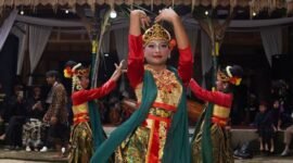 Seorang penari Jaipong dengan kostum warna-warni dan selendang yang melambai anggun, tengah menampilkan gerakan lincah penuh ekspresi, mencerminkan semangat khas tarian tradisional Sunda. Tarian ini memadukan kekuatan dan keanggunan, menjadi identitas budaya yang terus dijaga kelestariannya.
