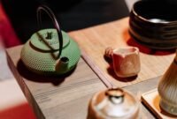 Seorang wanita sedang menyeduh teh hijau dengan cermat, menunjukkan ritual yang tenang dan penuh perhatian dalam mempersiapkan minuman sehat ini. Proses penyeduhan yang tepat sangat penting untuk mengeluarkan seluruh khasiat dan aroma alami dari daun teh hijau berkualitas.