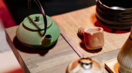 Seorang wanita sedang menyeduh teh hijau dengan cermat, menunjukkan ritual yang tenang dan penuh perhatian dalam mempersiapkan minuman sehat ini. Proses penyeduhan yang tepat sangat penting untuk mengeluarkan seluruh khasiat dan aroma alami dari daun teh hijau berkualitas.