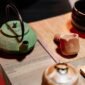Seorang wanita sedang menyeduh teh hijau dengan cermat, menunjukkan ritual yang tenang dan penuh perhatian dalam mempersiapkan minuman sehat ini. Proses penyeduhan yang tepat sangat penting untuk mengeluarkan seluruh khasiat dan aroma alami dari daun teh hijau berkualitas.