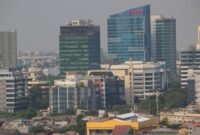 Seorang individu melakukan meditasi di tengah lanskap kota Jakarta yang sibuk, menunjukkan bagaimana ketenangan dapat ditemukan di antara gedung-gedung tinggi. Pemandangan ini merefleksikan upaya banyak warga urban dalam mencari keseimbangan dan kebahagiaan di tengah kecepatan hidup perkotaan.