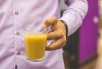 Seorang wanita sedang menikmati segelas jamu kunyit asam yang kaya rempah, mencerminkan perpaduan antara tradisi dan gaya hidup sehat modern. Minuman herbal ini semakin digemari sebagai alternatif alami untuk menjaga kesehatan tubuh.