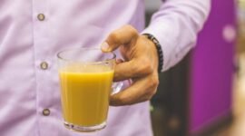 Seorang wanita sedang menikmati segelas jamu kunyit asam yang kaya rempah, mencerminkan perpaduan antara tradisi dan gaya hidup sehat modern. Minuman herbal ini semakin digemari sebagai alternatif alami untuk menjaga kesehatan tubuh.
