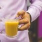 Seorang wanita sedang menikmati segelas jamu kunyit asam yang kaya rempah, mencerminkan perpaduan antara tradisi dan gaya hidup sehat modern. Minuman herbal ini semakin digemari sebagai alternatif alami untuk menjaga kesehatan tubuh.