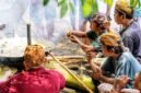 Seorang ibu sedang meracik jamu tradisional dengan bahan-bahan alami segar di dapur, menggambarkan proses otentik pembuatan minuman berkhasiat yang kaya akan rempah khas Indonesia.