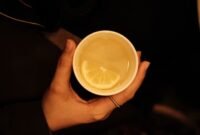 Secangkir teh hijau hangat mengepul dengan daun teh yang terlihat jelas, melambangkan minuman kaya antioksidan yang menyegarkan dan bermanfaat bagi kesehatan. Minuman ini telah lama menjadi bagian tak terpisahkan dari budaya hidup sehat di banyak belahan dunia.